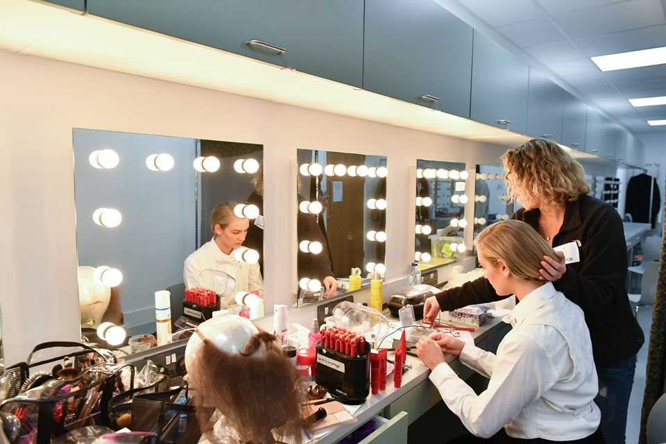 A group of opera students preparing for an opera performance, with a opera staff supporting.